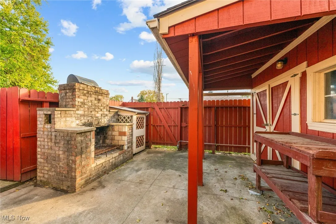 Fenced backyard with a patio and an outdoor brick fireplace