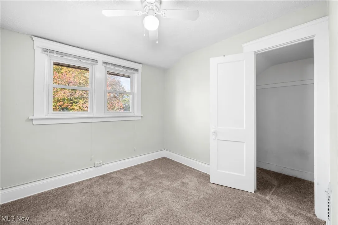 Unfurnished bedroom featuring lofted ceiling, carpet flooring, a ceiling fan, and a textured ceiling