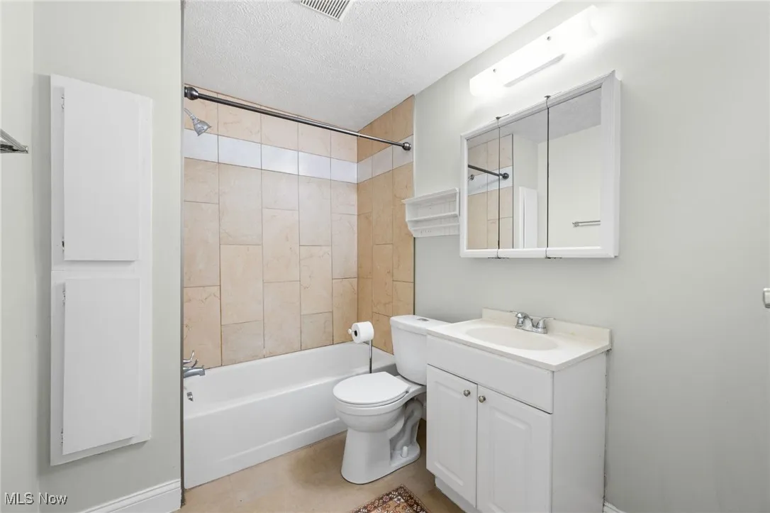 Bathroom with vanity, a textured ceiling, and bathing tub / shower combination
