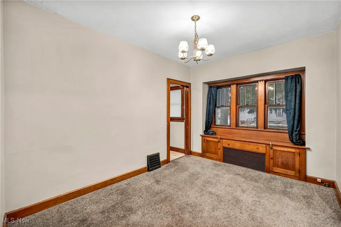 Unfurnished room with carpet flooring and a chandelier
