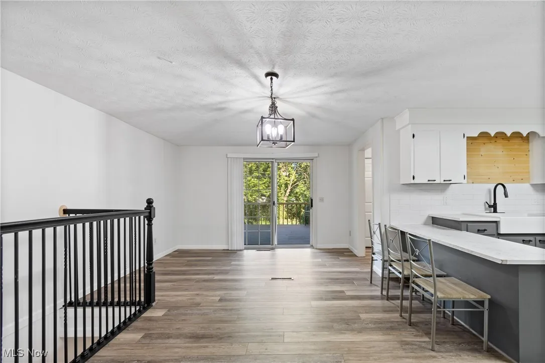 Kitchen featuring white cabinets, light wood-style flooring, a kitchen bar, pendant lighting, and decorative backsplash