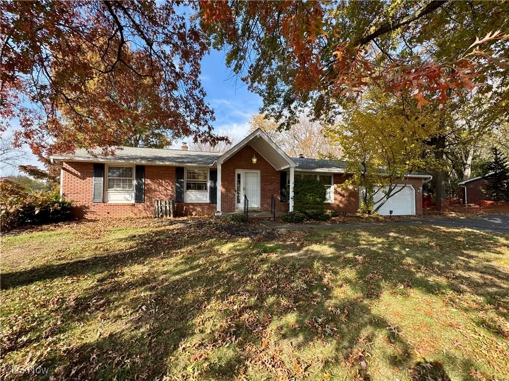 Ranch-style house featuring a front yard, brick siding, a garage, and a chimney