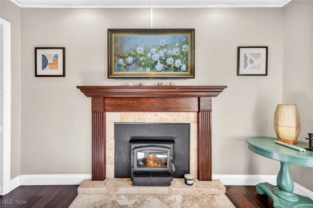 Detailed view of crown molding, wood finished floors, and a wood stove