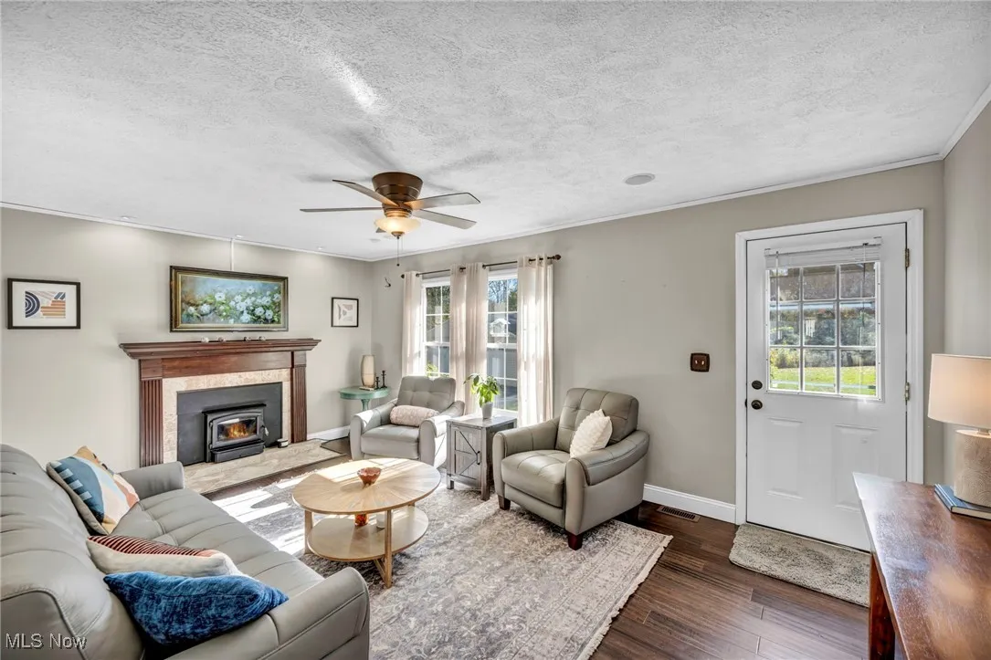 Living room with dark wood-style floors, a textured ceiling, a ceiling fan, and crown molding
