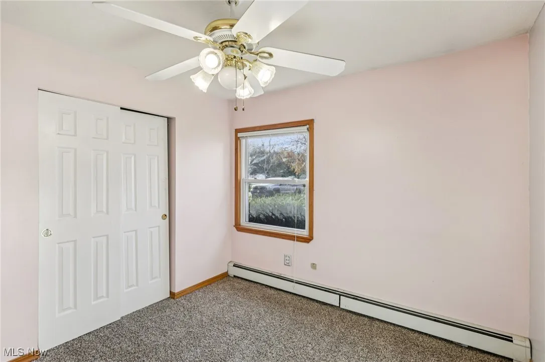 Unfurnished bedroom featuring baseboard heating, carpet floors, ceiling fan, and a closet