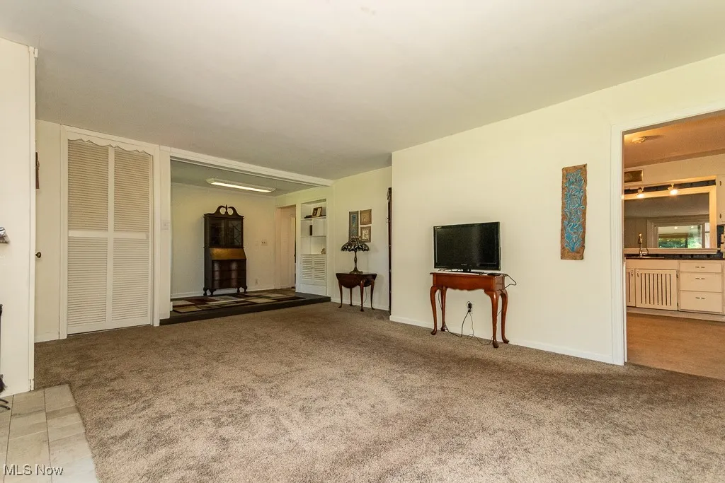 Unfurnished living room featuring light colored carpet and baseboards