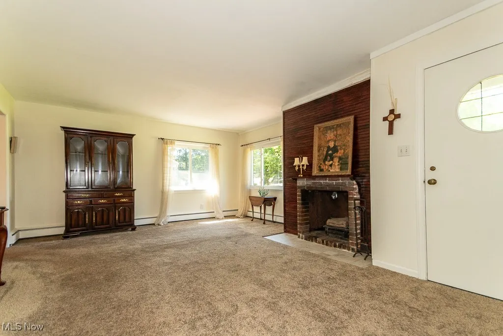 Unfurnished living room with a fireplace, carpet flooring, and baseboard heating