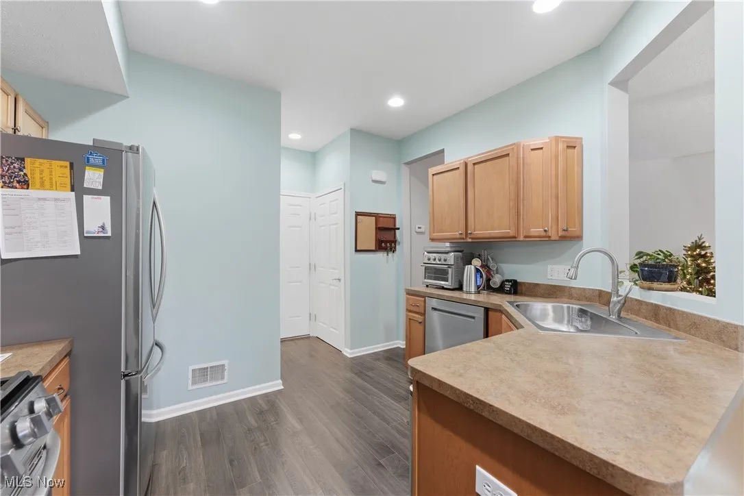 Kitchen featuring appliances with stainless steel finishes, dark wood-style flooring, recessed lighting, light countertops, and a peninsula