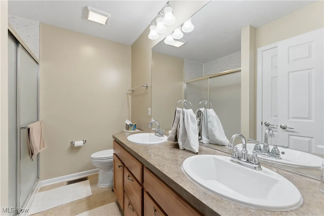 Full bath featuring double vanity, a stall shower, and light tile patterned flooring