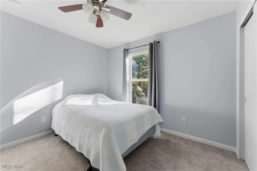 Bedroom with light colored carpet, a closet, and a ceiling fan
