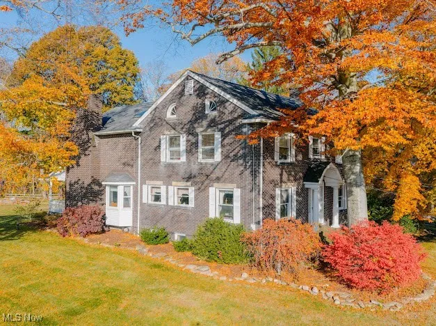 View of side of property with brick siding and a yard