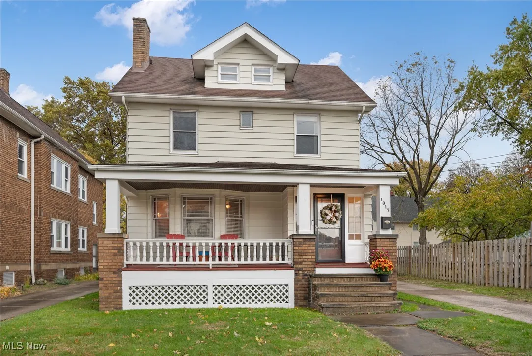 American foursquare style home featuring covered porch, a chimney, and roof with shingles
