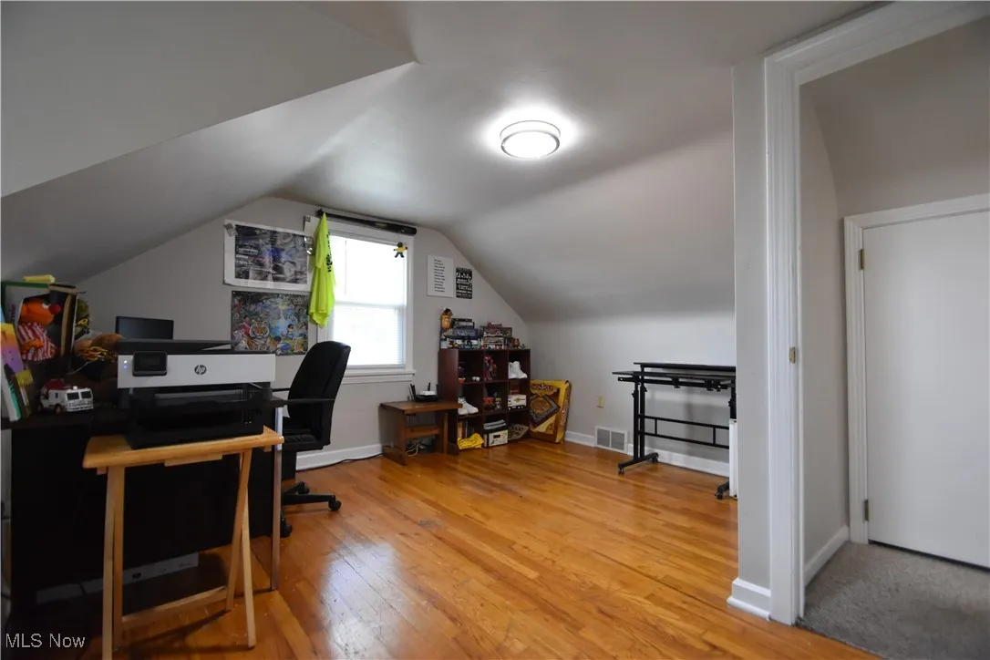 Office space featuring light wood-type flooring and lofted ceiling