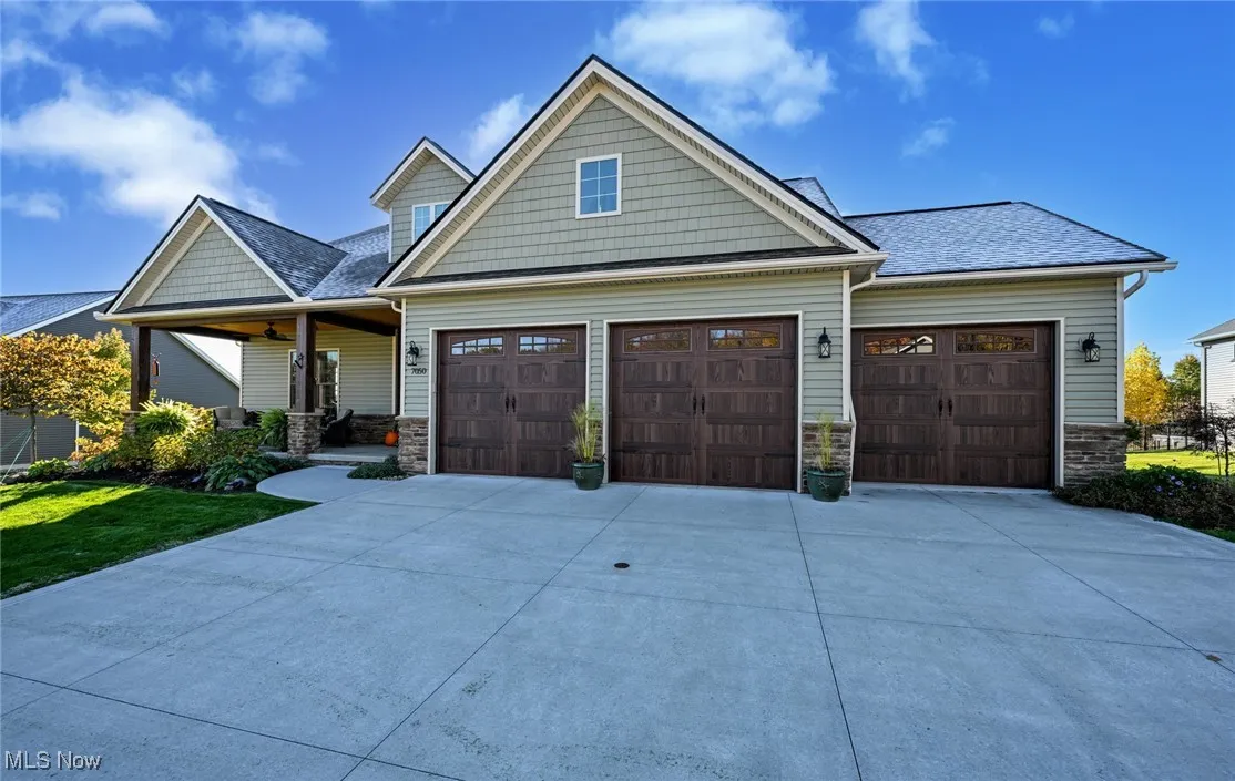 Craftsman-style home featuring stone siding, concrete driveway, a porch, roof with shingles, and an attached garage