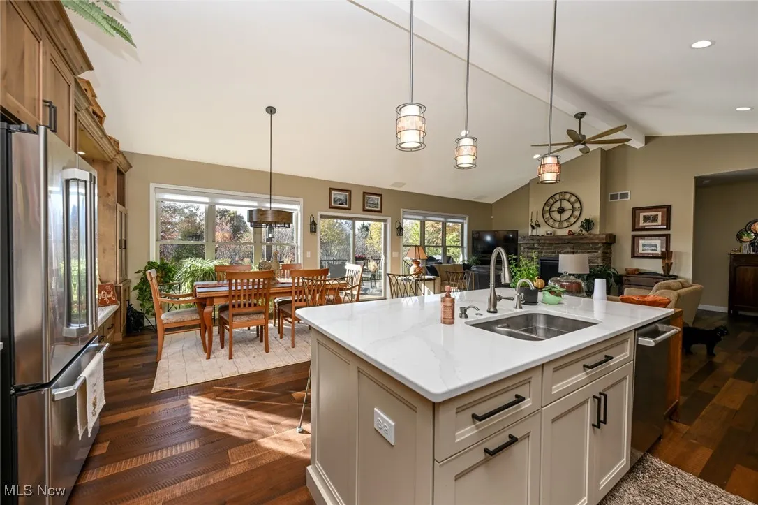 Kitchen featuring dark wood finished floors, stainless steel appliances, decorative light fixtures, and light stone counters
