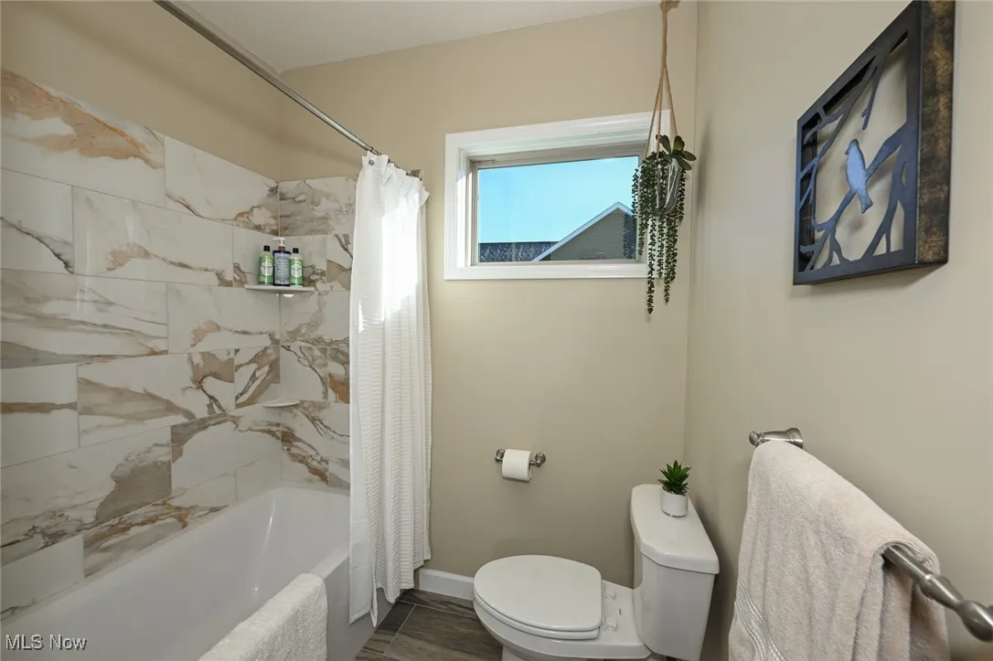 Full bathroom with shower / bath combination with curtain and baseboards