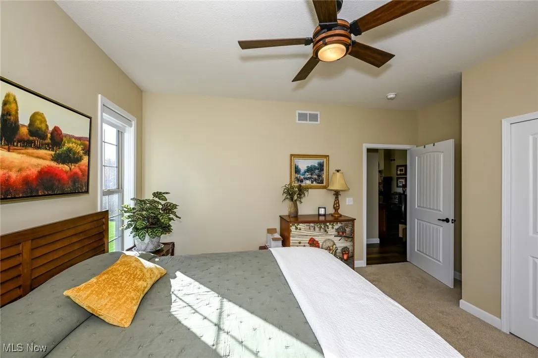 Bedroom with light colored carpet and a ceiling fan