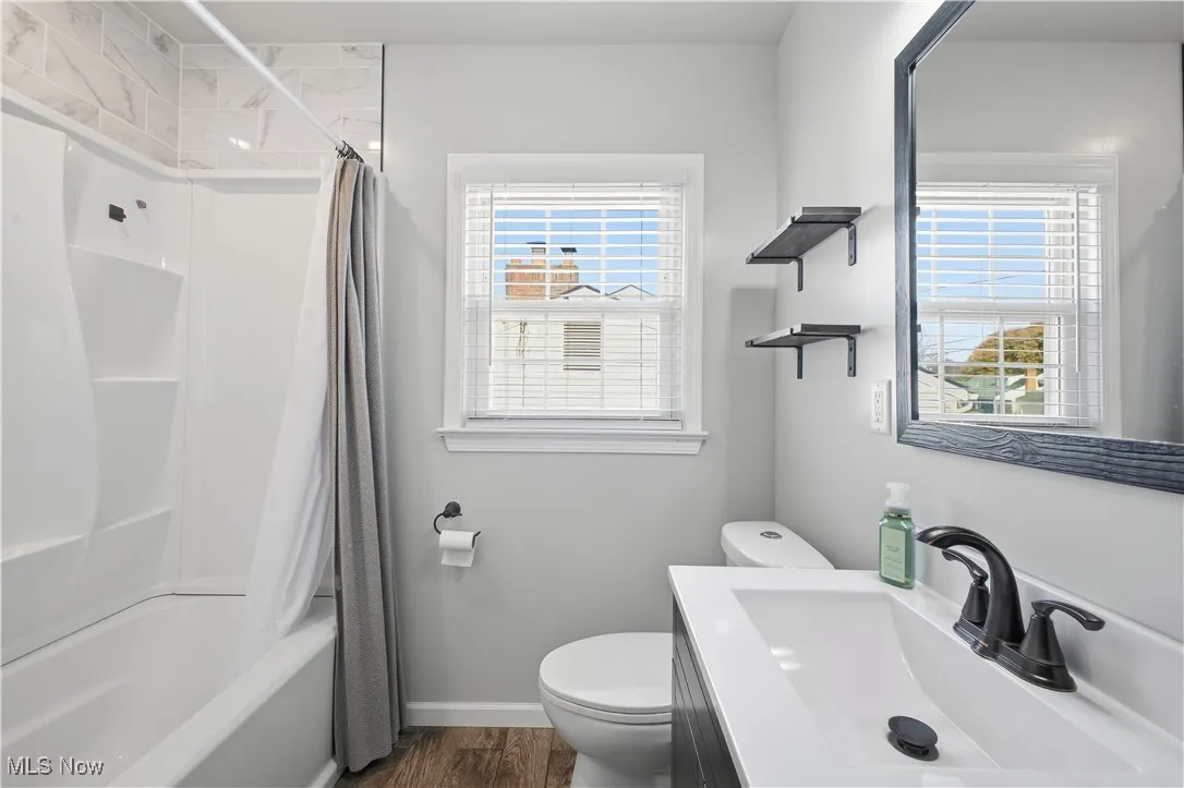 Bathroom with shower / bath combo with shower curtain, vanity, and dark wood finished floors