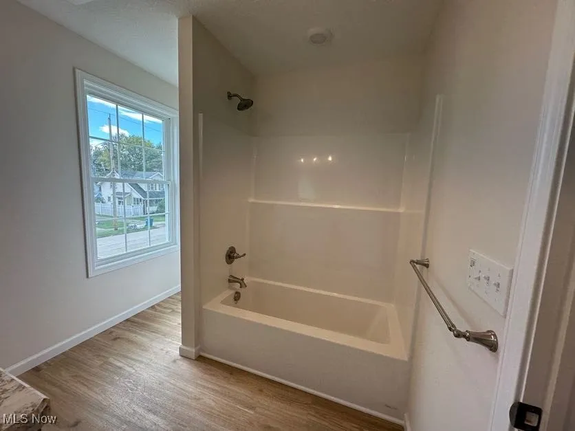 Bathroom featuring bathing tub / shower combination, wood-style floors, and a textured ceiling