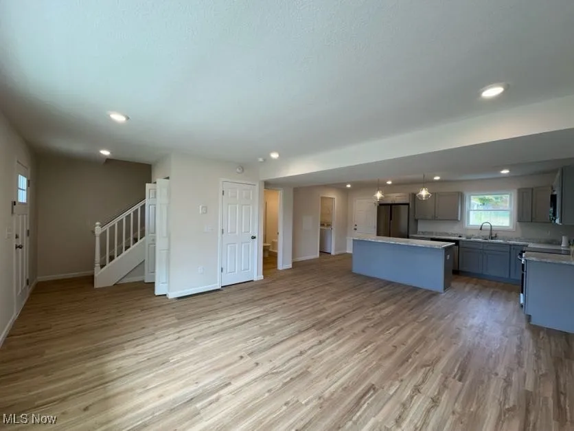 Kitchen featuring open floor plan, light wood-type flooring, a center island, recessed lighting, and stainless steel appliances