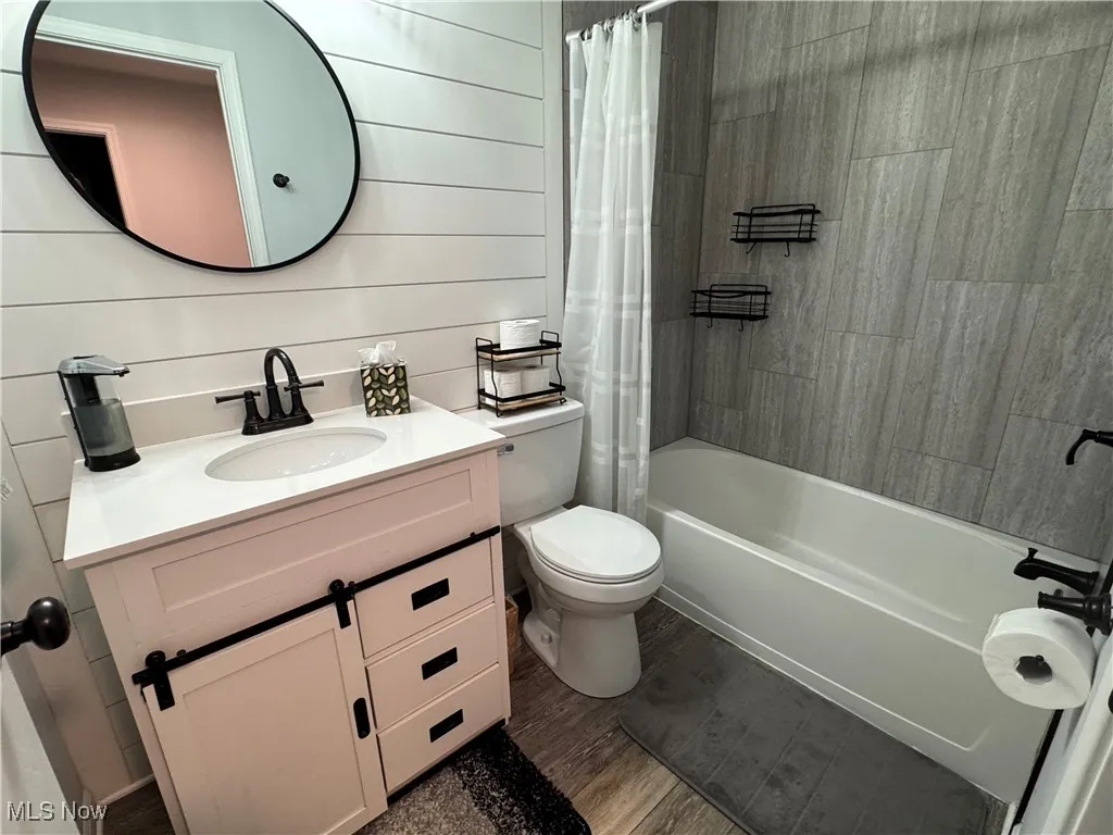 Bathroom with dark wood finished floors, vanity, and shower / bath combo with shower curtain