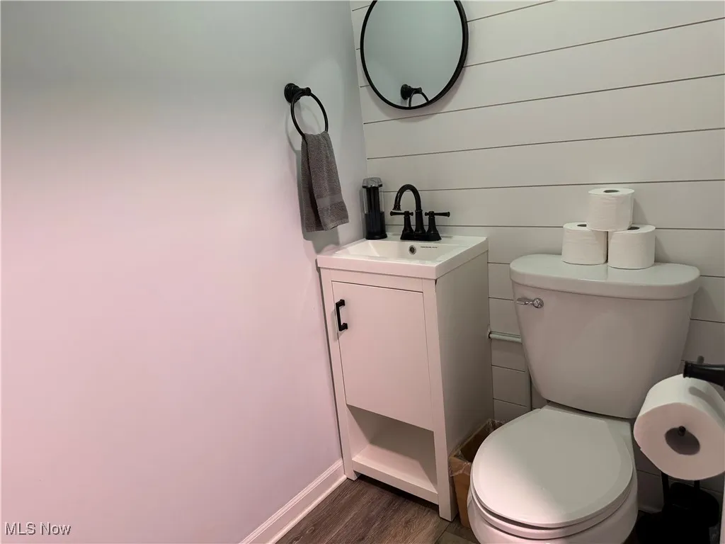 Half bathroom featuring vanity and dark wood-type flooring