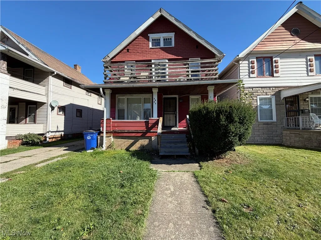 View of front of property featuring a front lawn, a balcony, and a porch