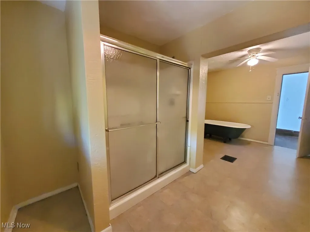 Full bathroom with a freestanding tub, ceiling fan, a stall shower, and light floors