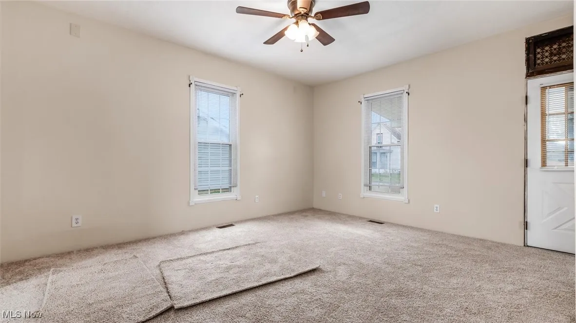 Unfurnished room with carpet floors, plenty of natural light, and a ceiling fan