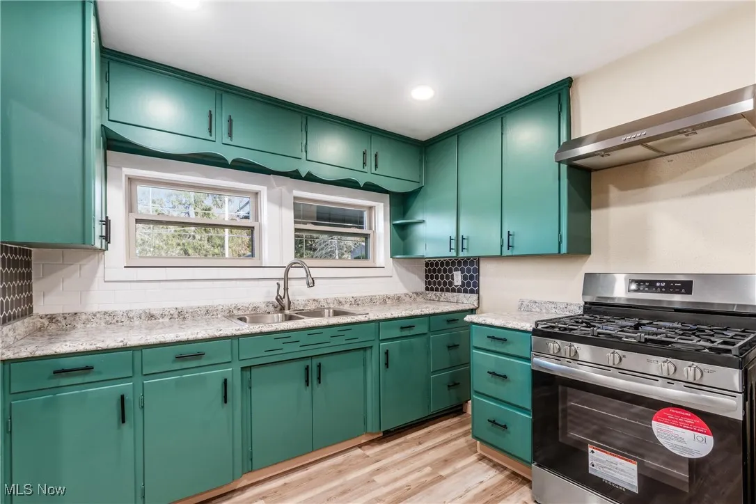 Kitchen featuring green cabinets, gas stove, light wood-type flooring, ventilation hood, and recessed lighting