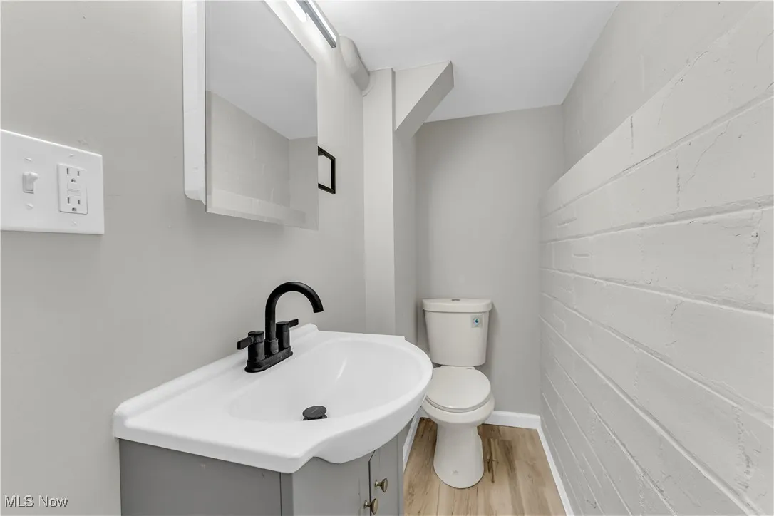 Half bathroom with light wood-type flooring and vanity