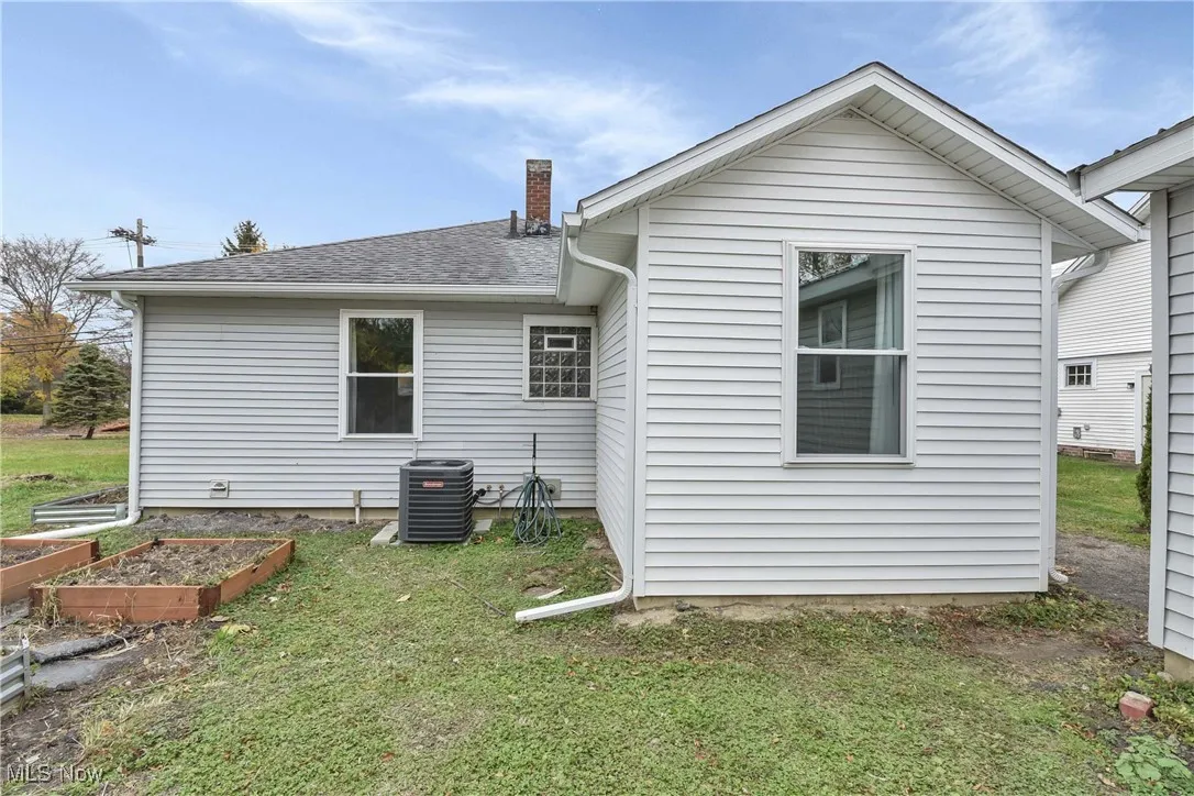 Rear view of house with a vegetable garden, a yard, a chimney, and a shingled roof