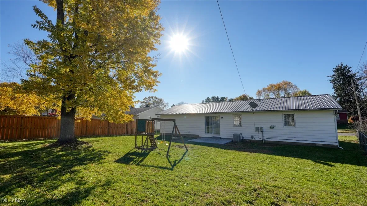 Back of property with a patio, a fenced backyard, and a metal roof
