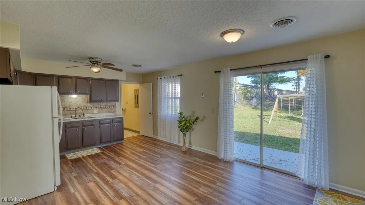 Kitchen with freestanding refrigerator, light countertops, backsplash, dark wood-style flooring, and a textured ceiling