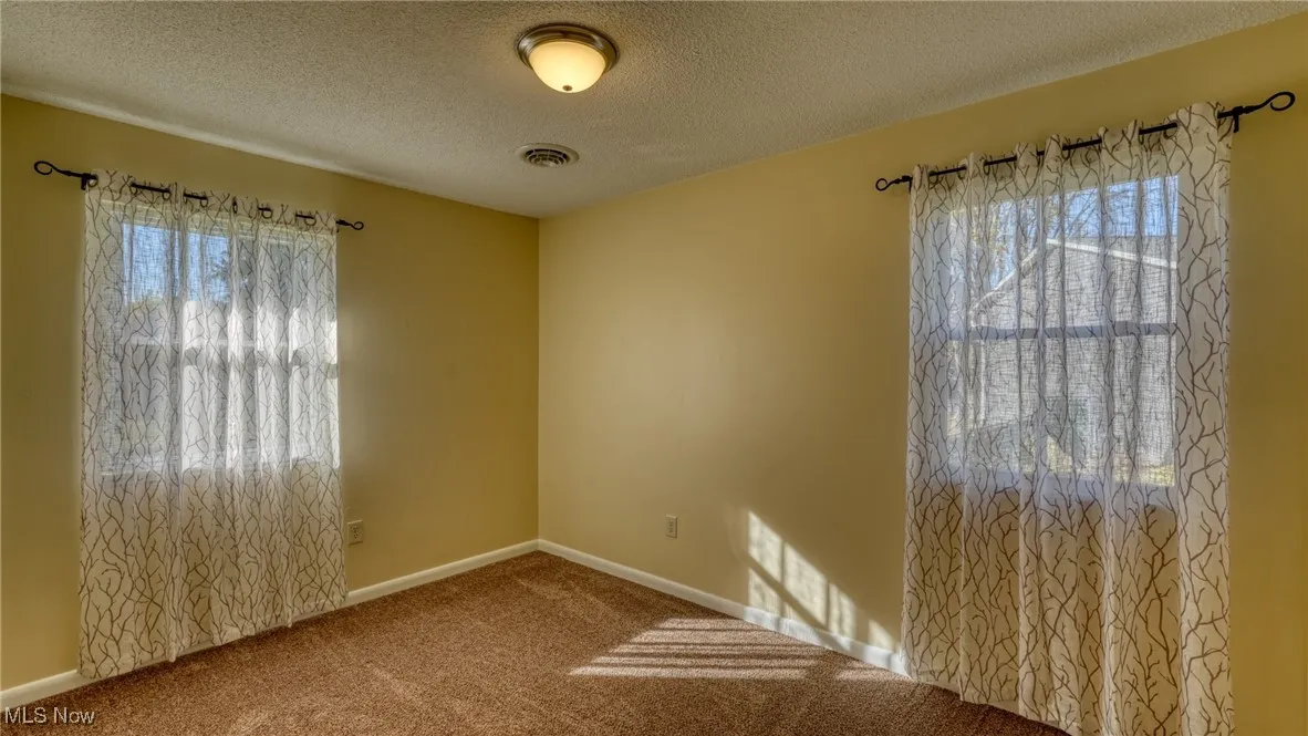 Unfurnished room with a textured ceiling and carpet floors