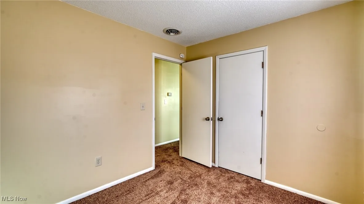 Unfurnished bedroom featuring a textured ceiling and dark colored carpet