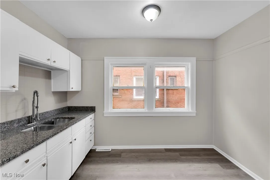 Kitchen featuring white cabinetry, dark stone countertops, and dark wood finished floors