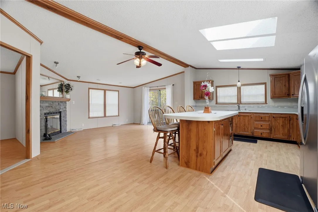 Kitchen with brown cabinetry, light countertops, a kitchen bar, light wood-style floors, and ornamental molding