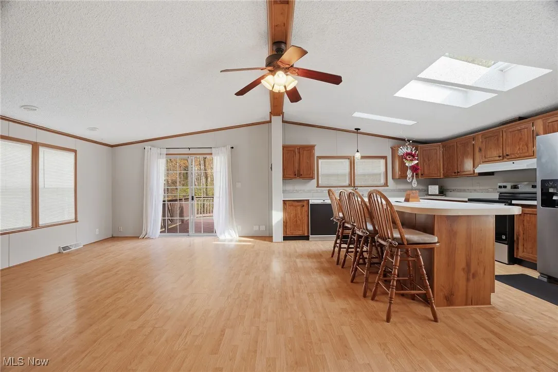 Kitchen featuring light countertops, brown cabinets, appliances with stainless steel finishes, a textured ceiling, and light wood-style floors