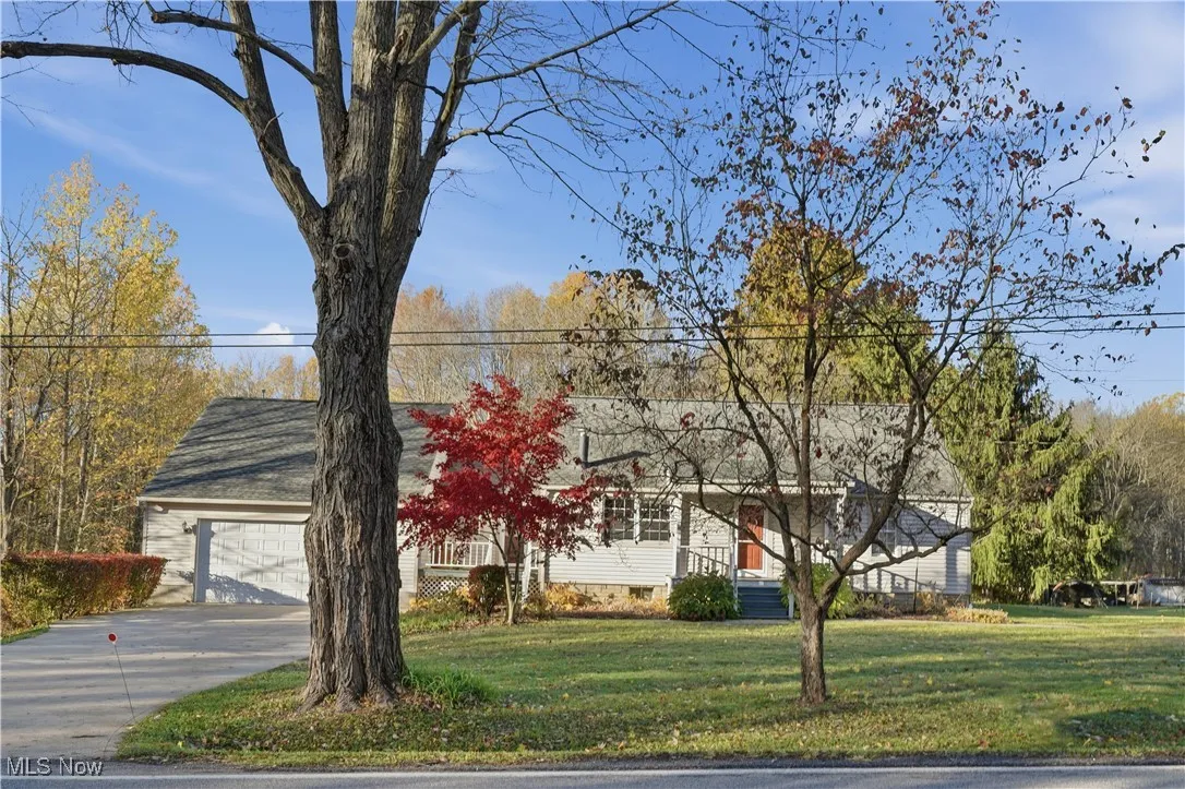 View of front facade featuring a front yard, concrete driveway, and a garage