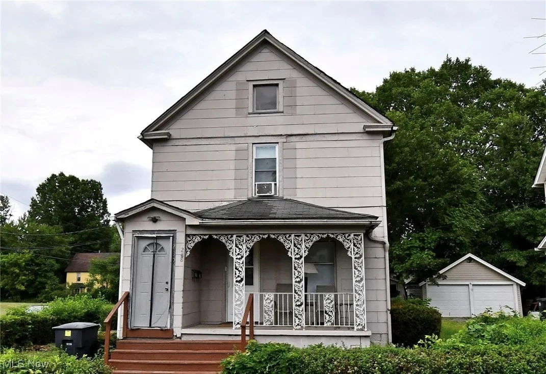 View of front of property with covered porch, an outbuilding, and a garage