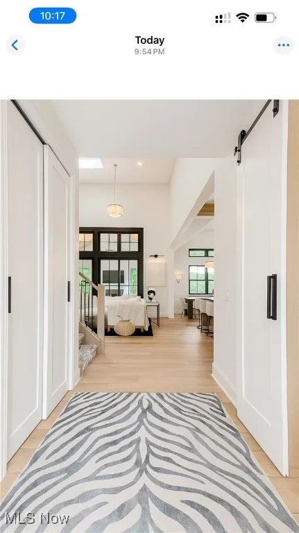 Corridor featuring a barn door, light wood-style floors, and recessed lighting