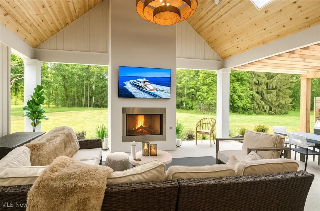 View of patio / terrace with view of wooded area and an outdoor living space with a fireplace