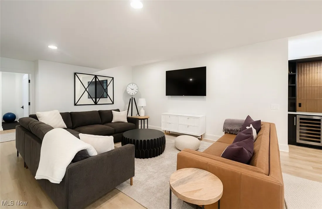 Living room with light wood finished floors, wine cooler, recessed lighting, and bar area