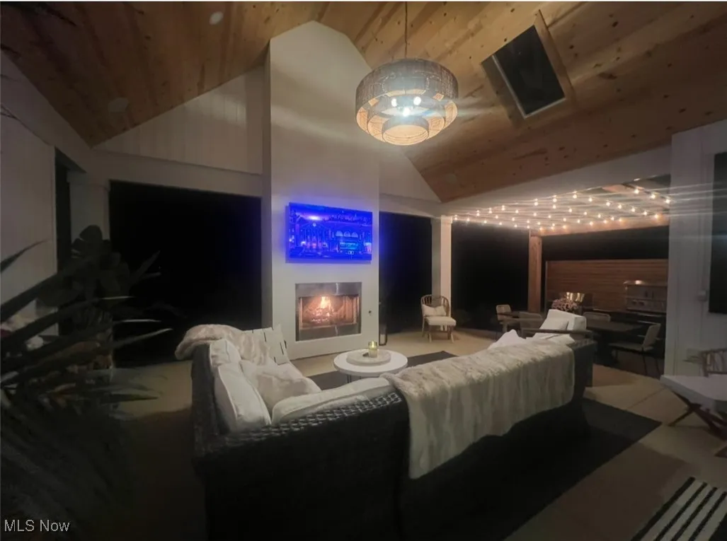 Cinema room featuring high vaulted ceiling and a lit fireplace