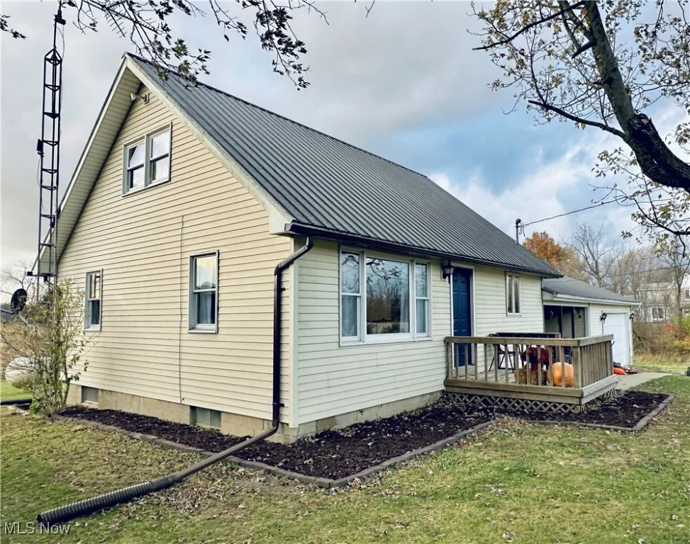 Rear view of house featuring a wooden deck, a metal roof, and a lawn