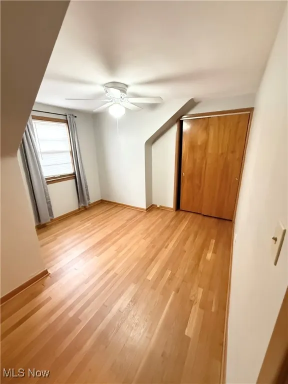 Unfurnished bedroom with light wood-style flooring, a ceiling fan, and a closet