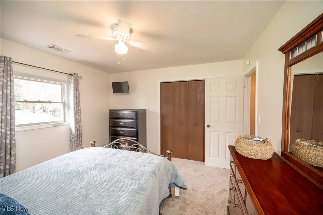 Primary bedroom with brand new carpet flooring, ceiling fan, and a closet