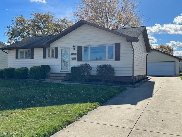 View of front of home with a front yard, an outbuilding, and a garage
