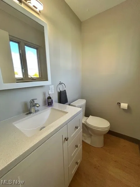 Attached Half bath featuring dark wood-type flooring and vanity